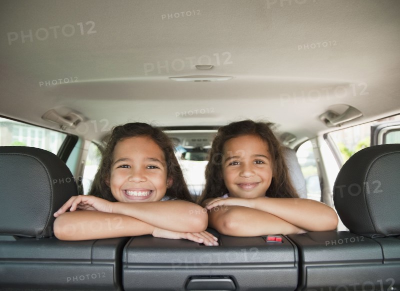 Hispanic sisters in back seat of car