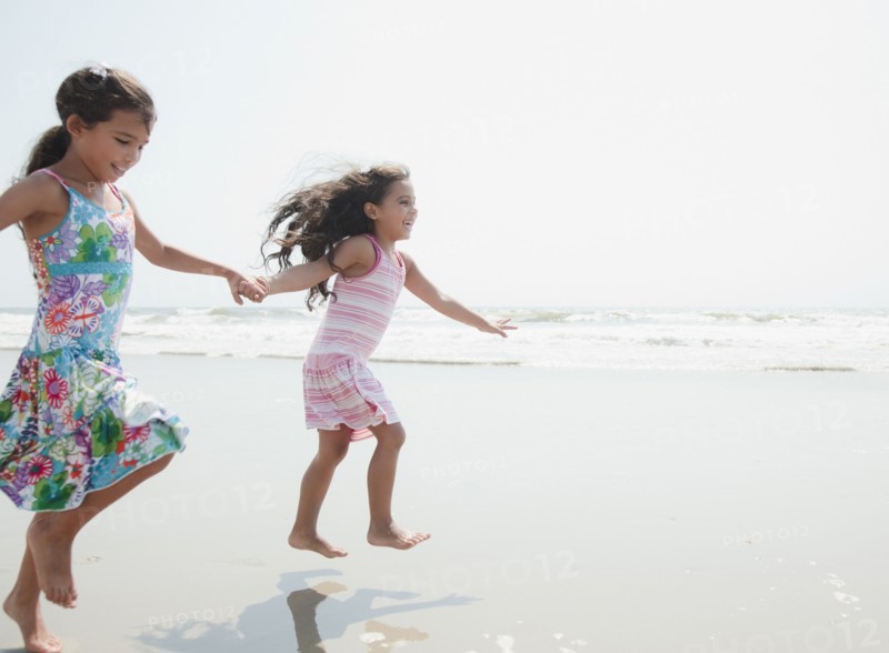 Hispanic sisters playing at beach