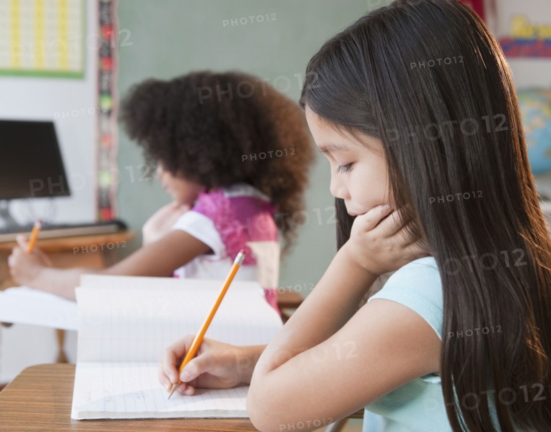 Mixed race school girl writing in notebook