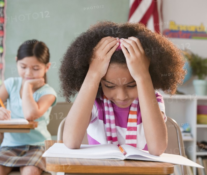 School girl reading book in classroom