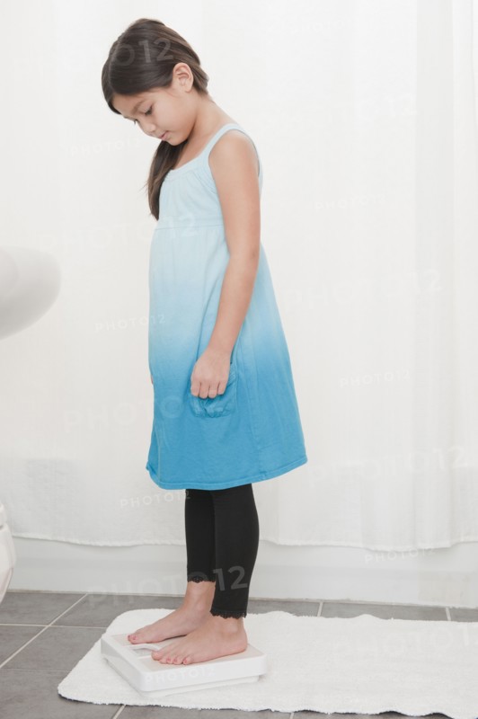 Mixed race girl weighing herself
