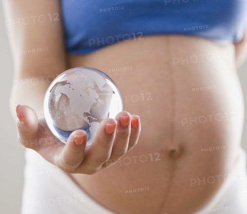 Pregnant Hispanic woman holding glass globe