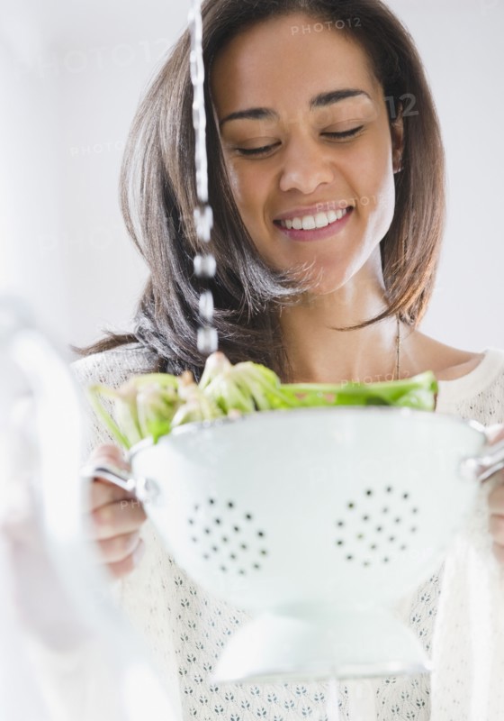 Mixed race woman rinsing spinach