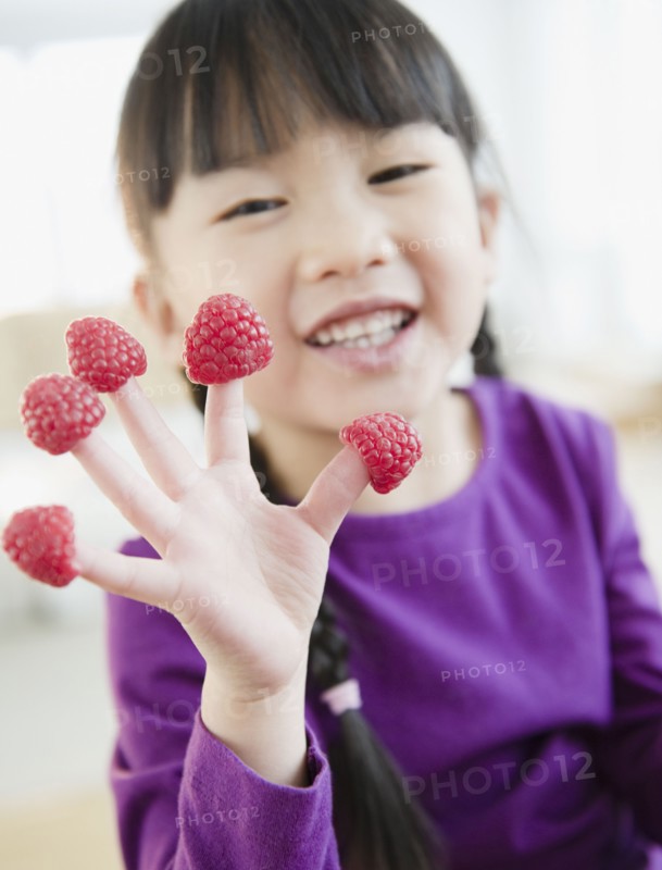 Chinese girl with raspberries on fingers