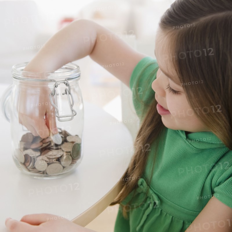 Mixed race girl taking coin out of jar