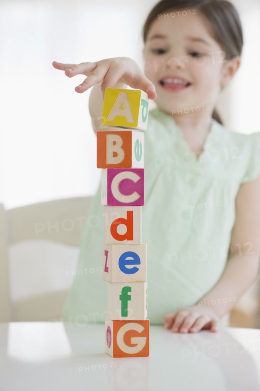 Mixed race girl stacking alphabet blocks
