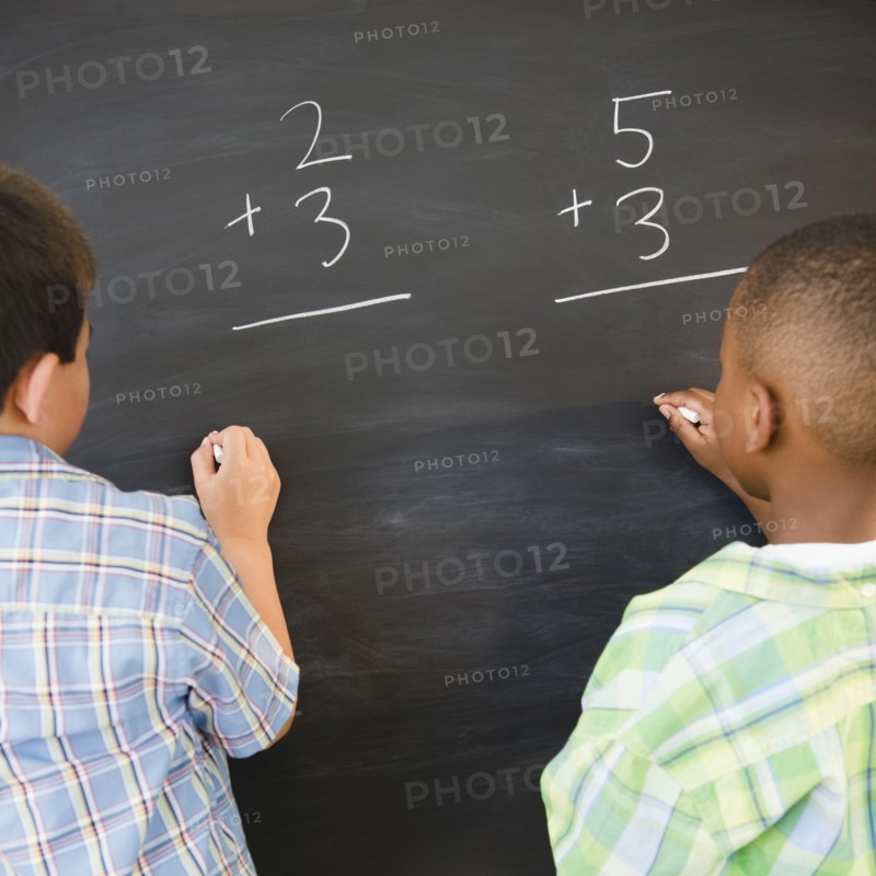 Boys solving math problems on blackboard