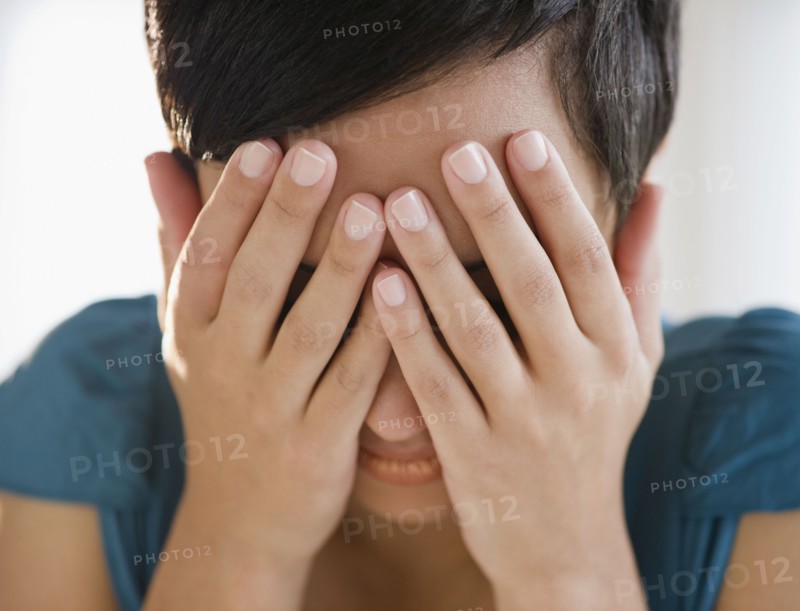 Mixed race woman covering face with hands