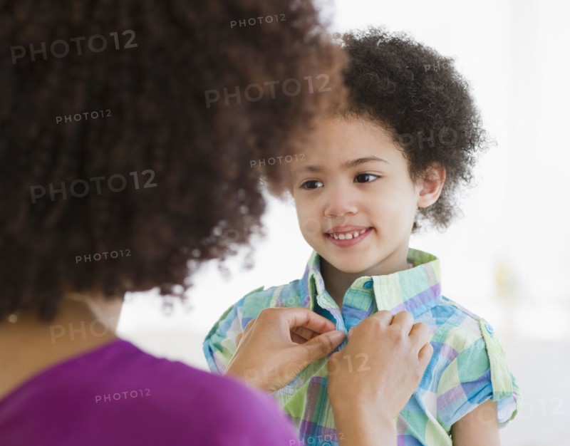 Mother buttoning shirt of daughter