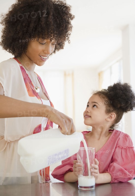 Mother pouring milk into glass for daughter