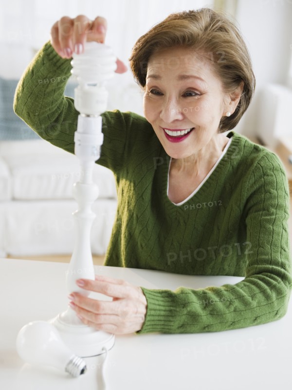 Japanese woman replacing energy efficient light bulb