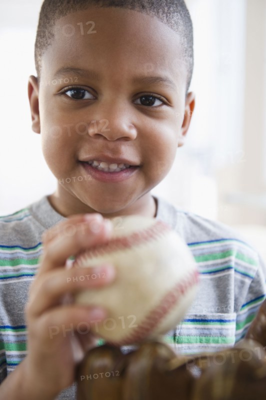 African American boy holding baseball and baseball glove