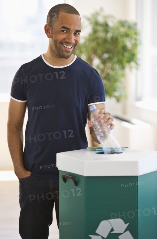 Mixed race man putting plastic bottle in recycling bin