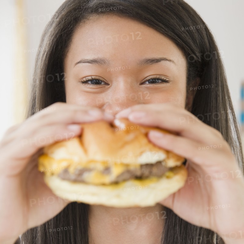 Close up of mixed race teenage girl eating cheeseburger