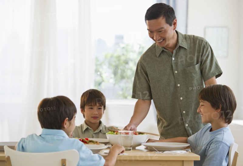 Father serving dinner to sons at table