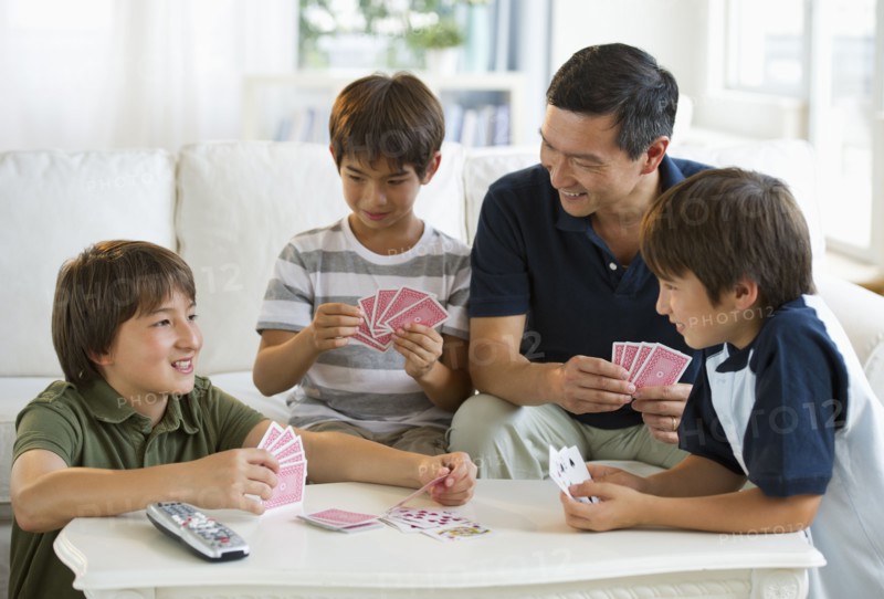 Father and sons playing cards in living room