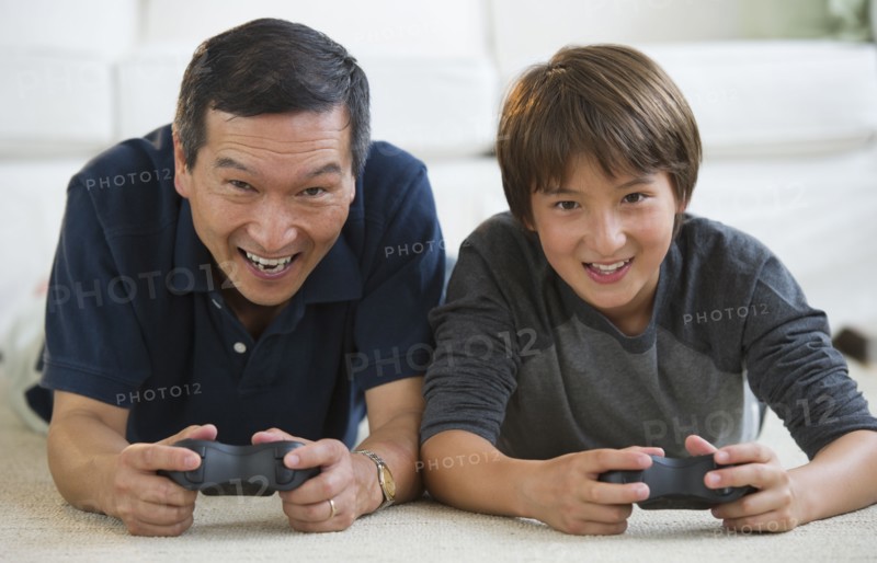 Father and son playing video game on living room floor
