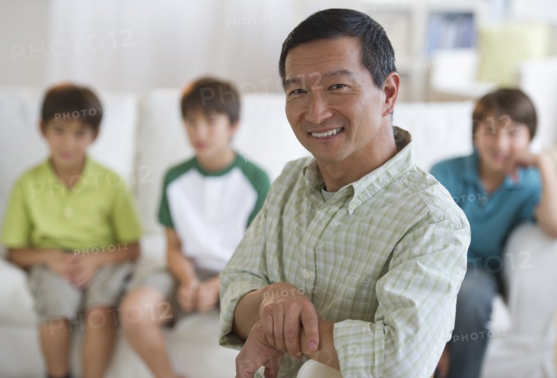 Smiling father in living room with sons in background