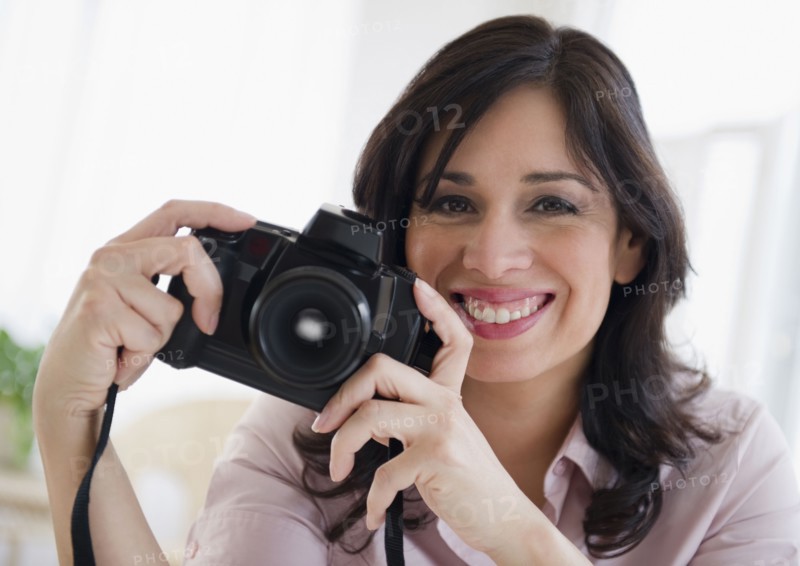 Smiling Hispanic woman holding digital camera