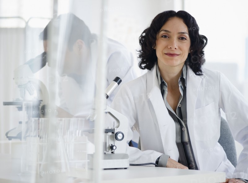 Hispanic researcher in laboratory next to microscope