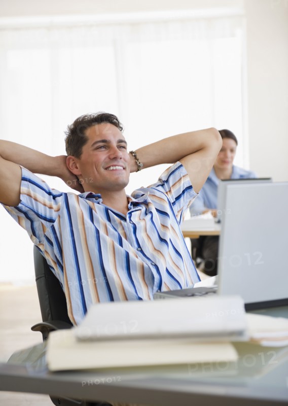 Mixed race businessman leaning back in chair at desk