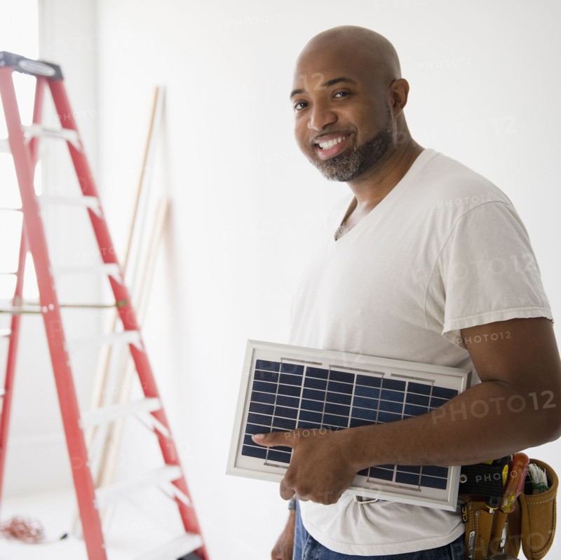 African American construction worker carrying solar panel