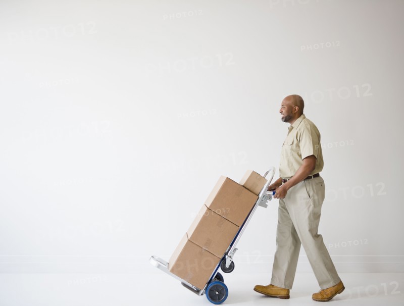 African American deliveryman pushing hand truck with boxes