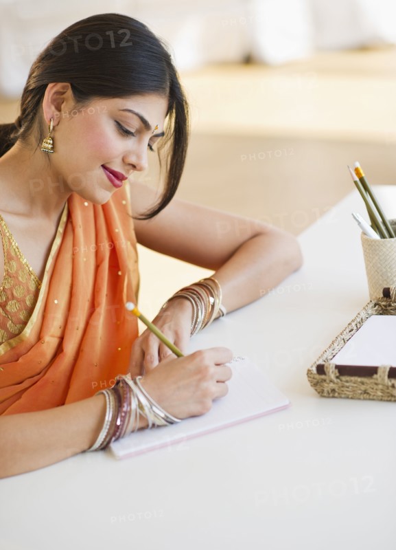 Indian woman in traditional Indian clothing writing in notebook