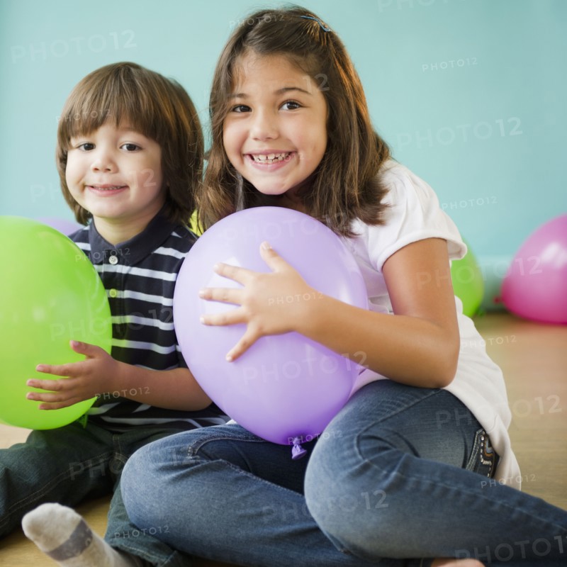 Hispanic brother and sister holding balloons