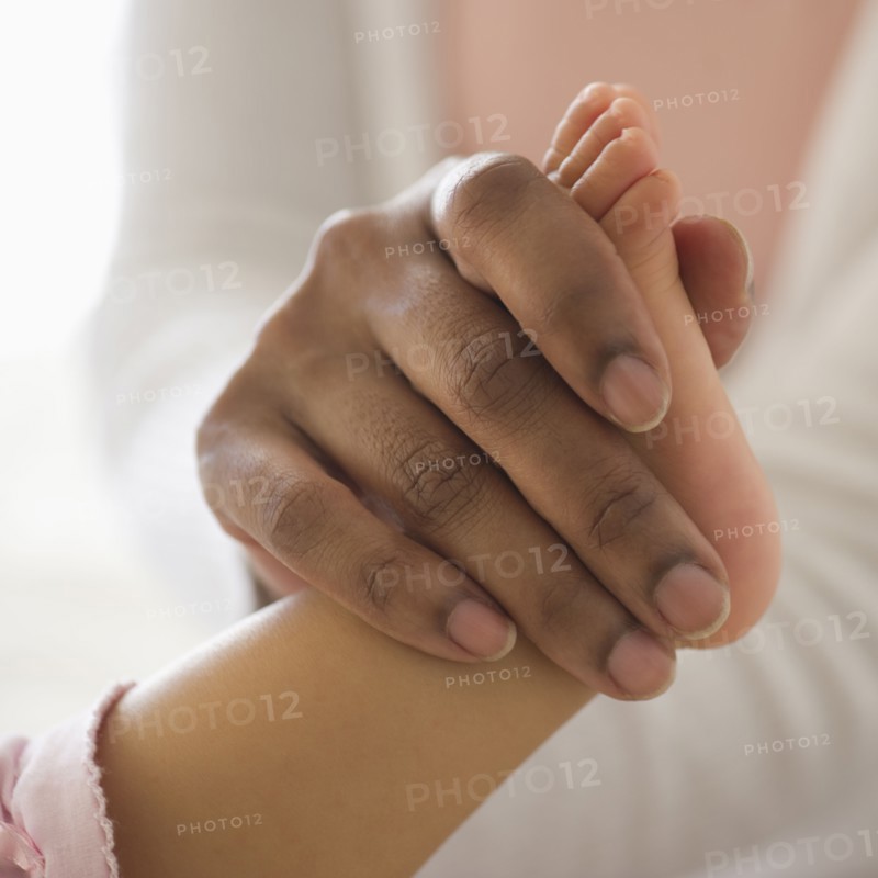 Mixed race woman holding babyÕs foot