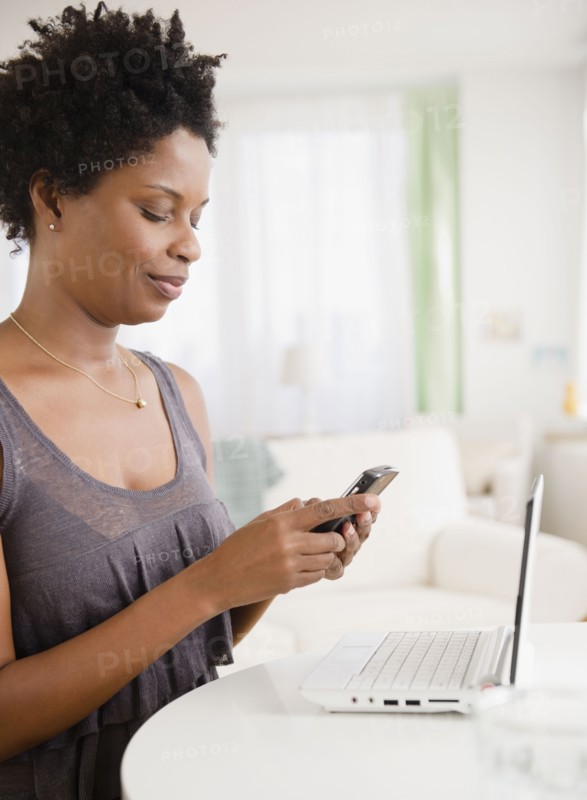 Black woman text messaging on cell phone