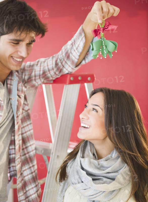 Man holding mistletoe over wife's head