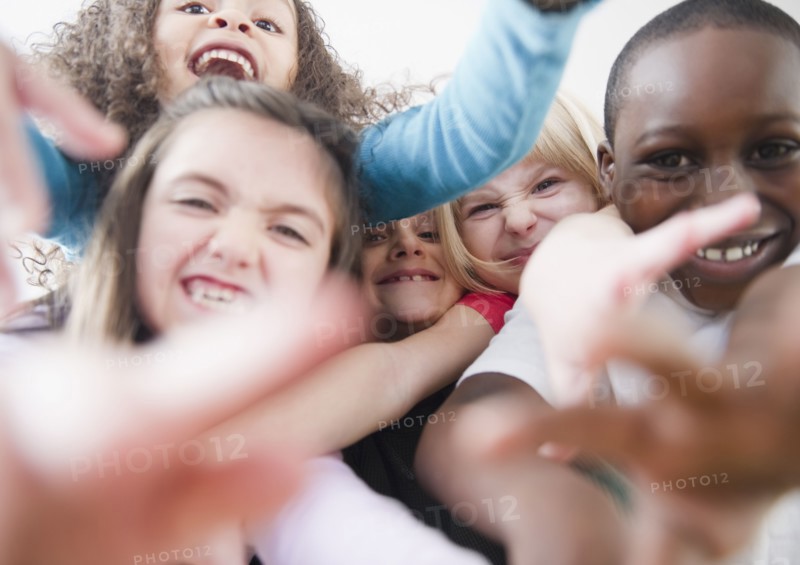 Grinning children reaching toward camera
