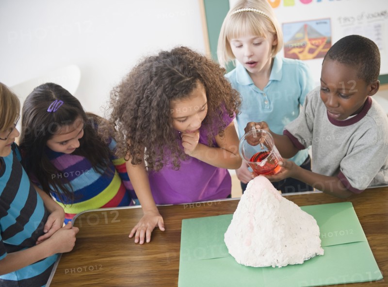 Children watching boy with model volcano