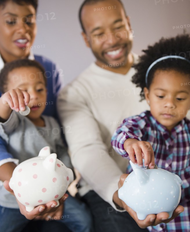 Black parents watching children put money in piggy bank
