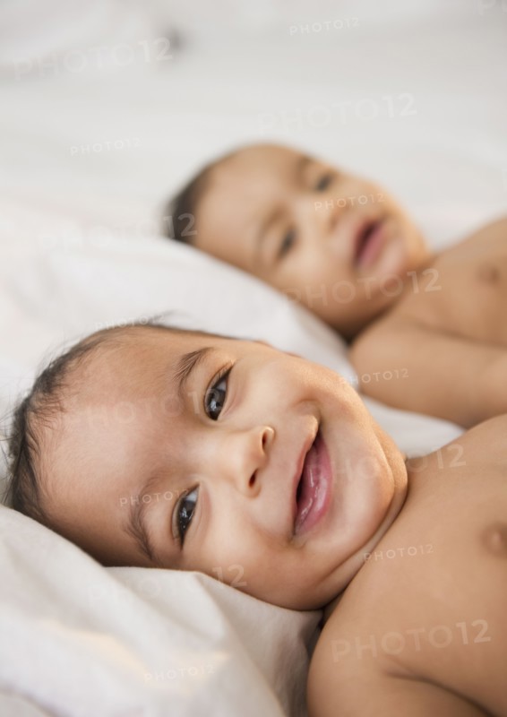Smiling mixed race twins laying together
