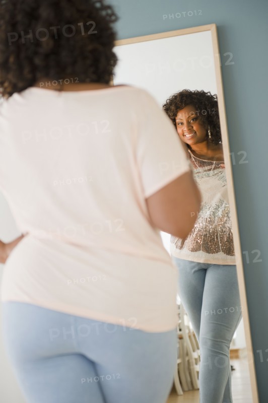 African American woman looking at reflection in mirror