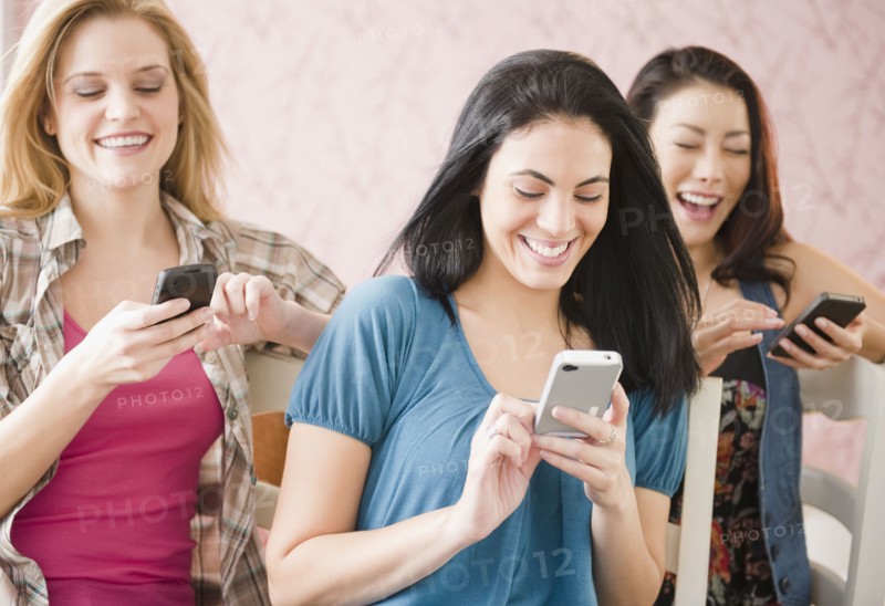 Friends text messaging on cell phones together