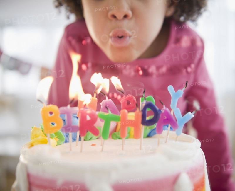 African American girl blowing out birthday candles