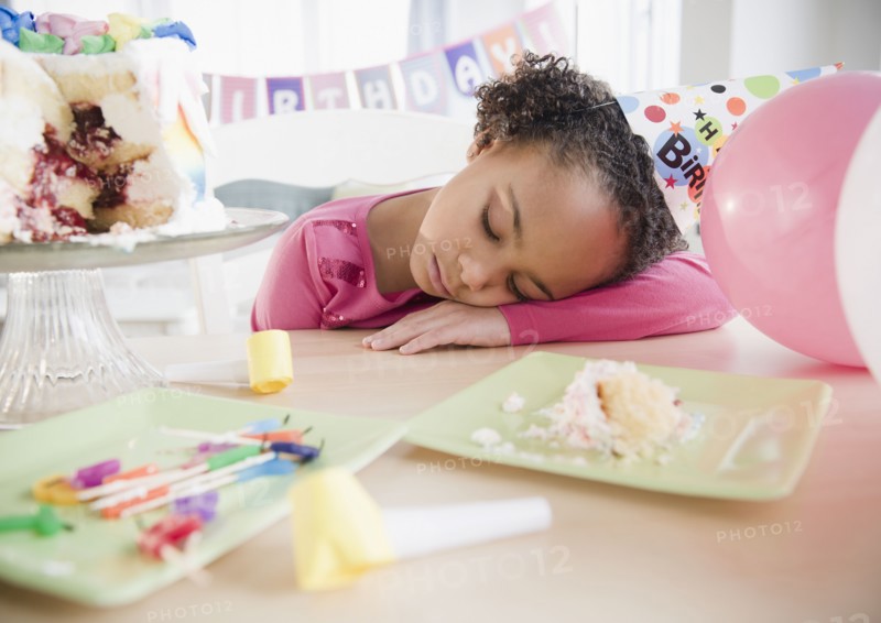 African American girl sleeping at birthday party
