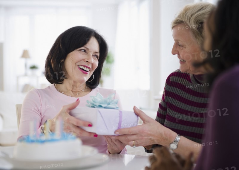Women surprising friend with birthday cake and gift