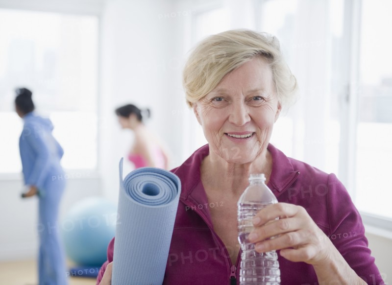 Caucasian woman with yoga mat drinking water