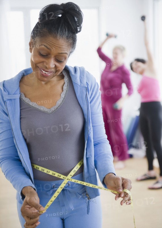 Mixed race woman measuring her waist