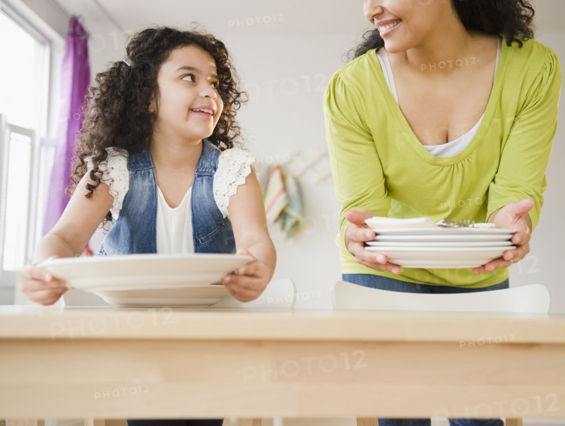 Mother and daughter setting the table