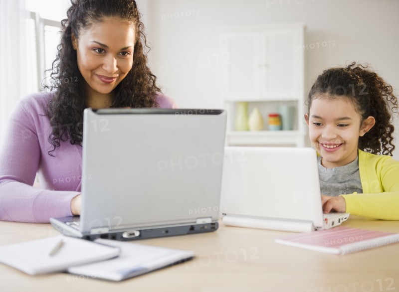 Mother and daughter using laptops together