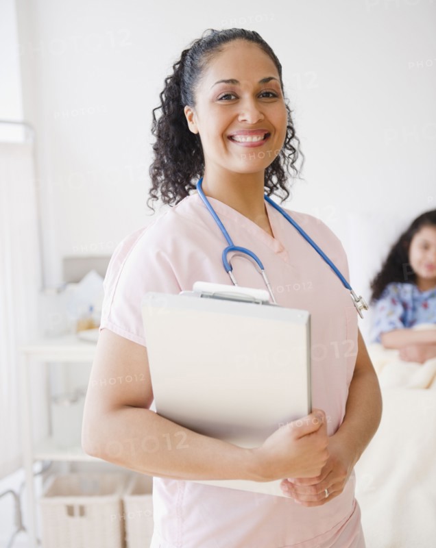 Smiling mixed race nurse in hospital room