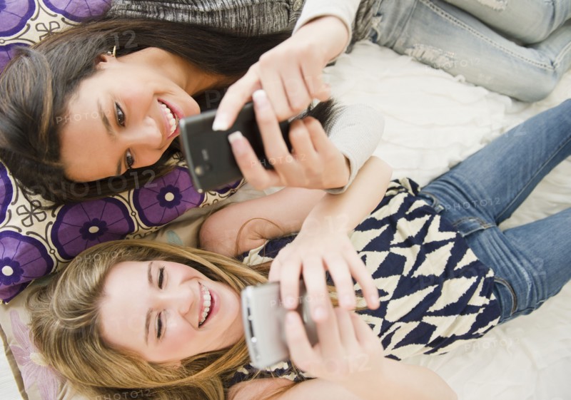 Teenage girls text messaging on cell phones