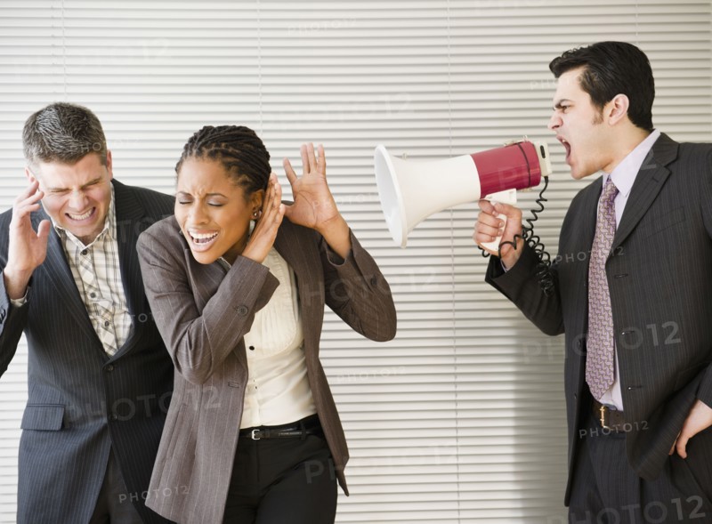 Businessman shouting through bullhorn at co-workers