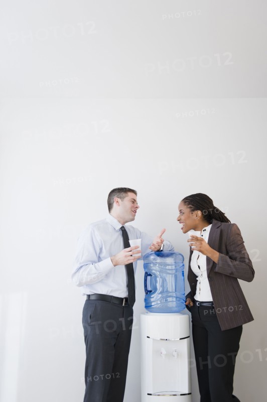 Business people talking together at water cooler
