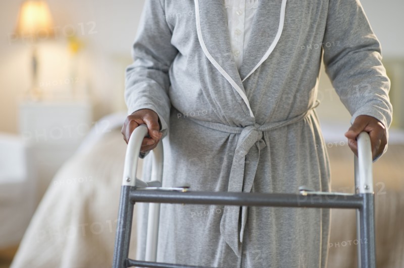 Black woman walking with walker in bedroom